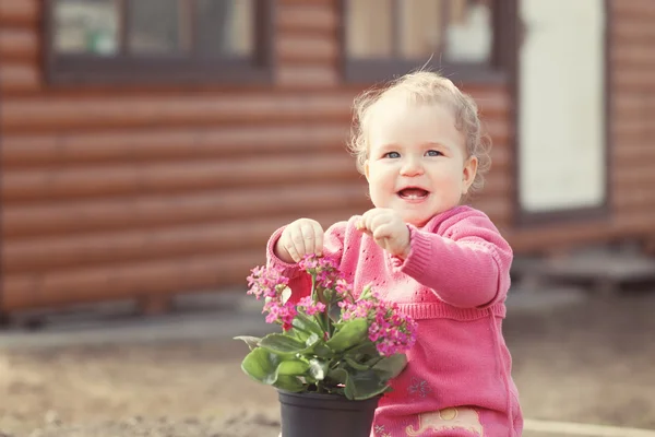 Bonito bebê menina no vestido rosa coloca flores — Fotografia de Stock