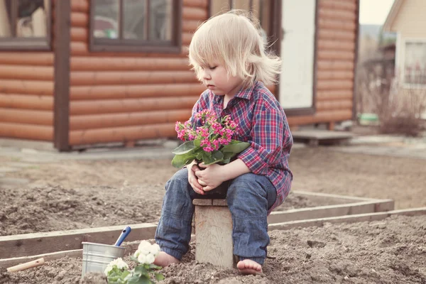 Bonito bebê menina no vestido rosa coloca flores — Fotografia de Stock