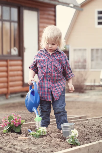 Bambina piantare e innaffiare fiori in giardino — Foto Stock