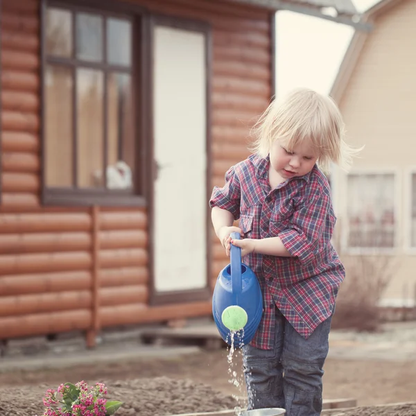 Kleines Mädchen pflanzt und gießt Blumen im Garten — Stockfoto