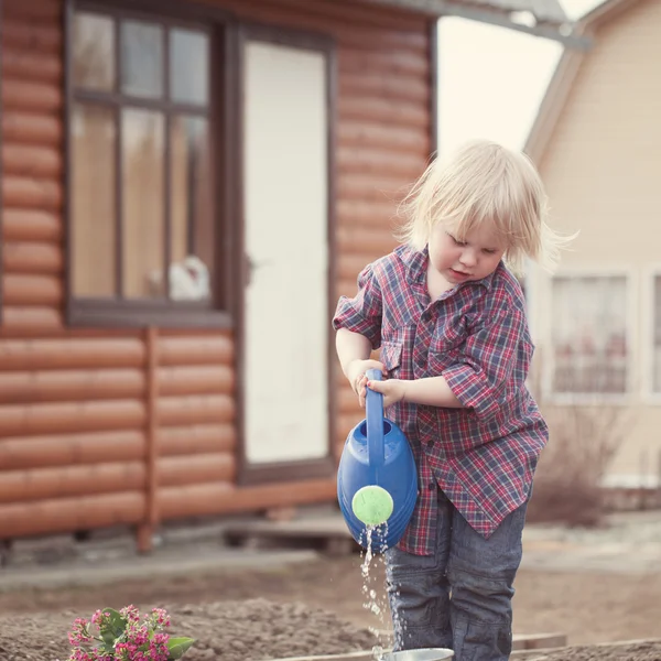 Niña plantando y regando flores en el jardín —  Fotos de Stock