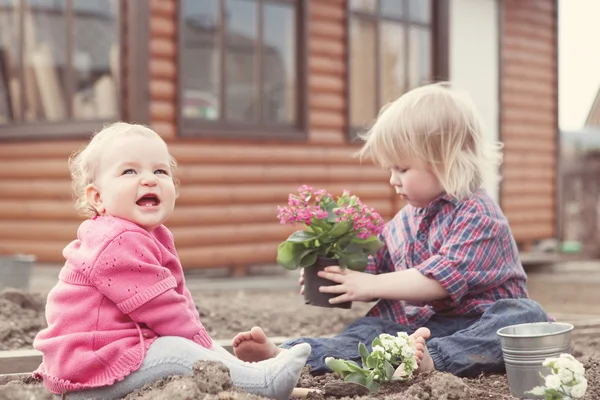 Cute baby girl in pink dress puts flowers Stock Photo