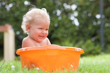 Neşeli mutlu sevimli kıvırcık bebek turuncu pelvis içinde boğulmuş olduğunu