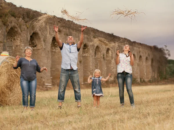 Glad familj kul på fältet med höstackar — Stockfoto