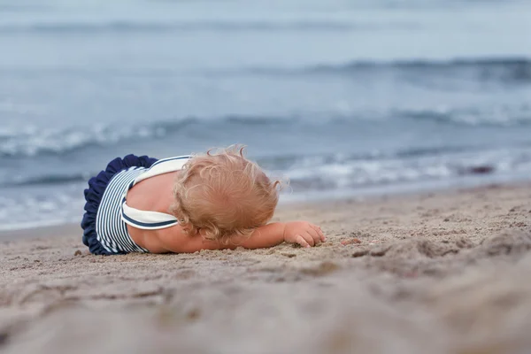 Little pretty kid in bathing suit lying on beach — Stock Photo, Image