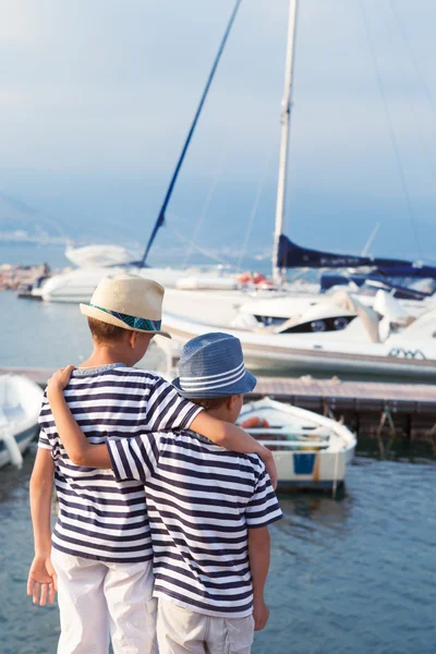 Dos hermanos abrazan y miran barcos, yates en el mar — Foto de Stock