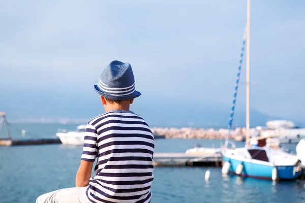Kind mit Hut blickt auf See und Schiff — Stockfoto