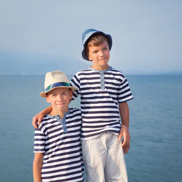 Dos hermanos abrazan y miran barcos, yates en el mar — Foto de Stock