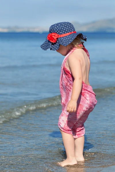 Счастливая девушка в шляпе и солнцезащитных очках, гуляющая у моря — стоковое фото
