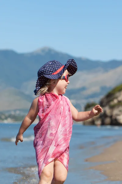 Chica feliz en sombrero y gafas de sol, caminando cerca del mar — Foto de Stock