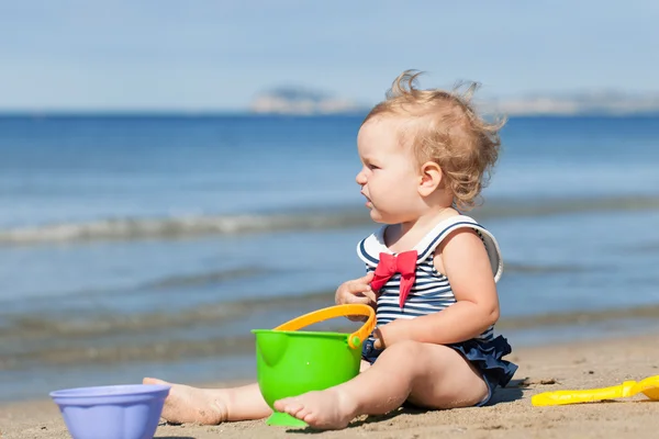 Happy cute girl in swimsuit playing with sand on beach — Stock Photo, Image