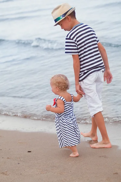 Happy older brother and younger cute sister walking on sea coast — Stock Photo, Image