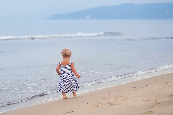 Маленькая хорошенькая девочка идет вдоль берега моря — стоковое фото