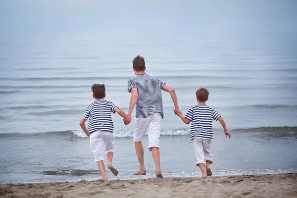 Three merry, happy, brother plays at sea — Stock Photo, Image