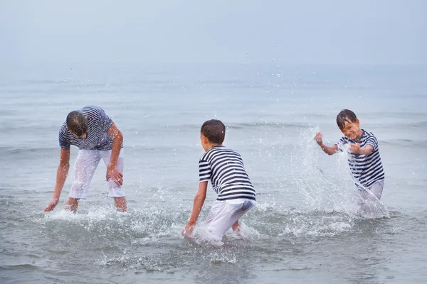 Three merry, happy, brother plays at sea — Stock Photo, Image