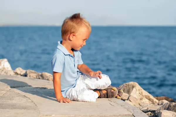 Feliz lindo niño sentado en la arena en la playa — Foto de Stock