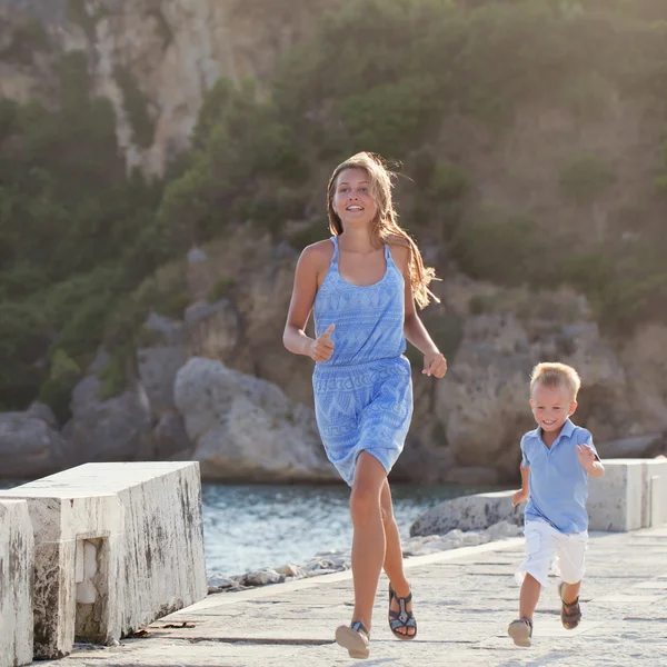 Feliz linda hermana mayor y hermano pequeño sentado en la playa — Foto de Stock