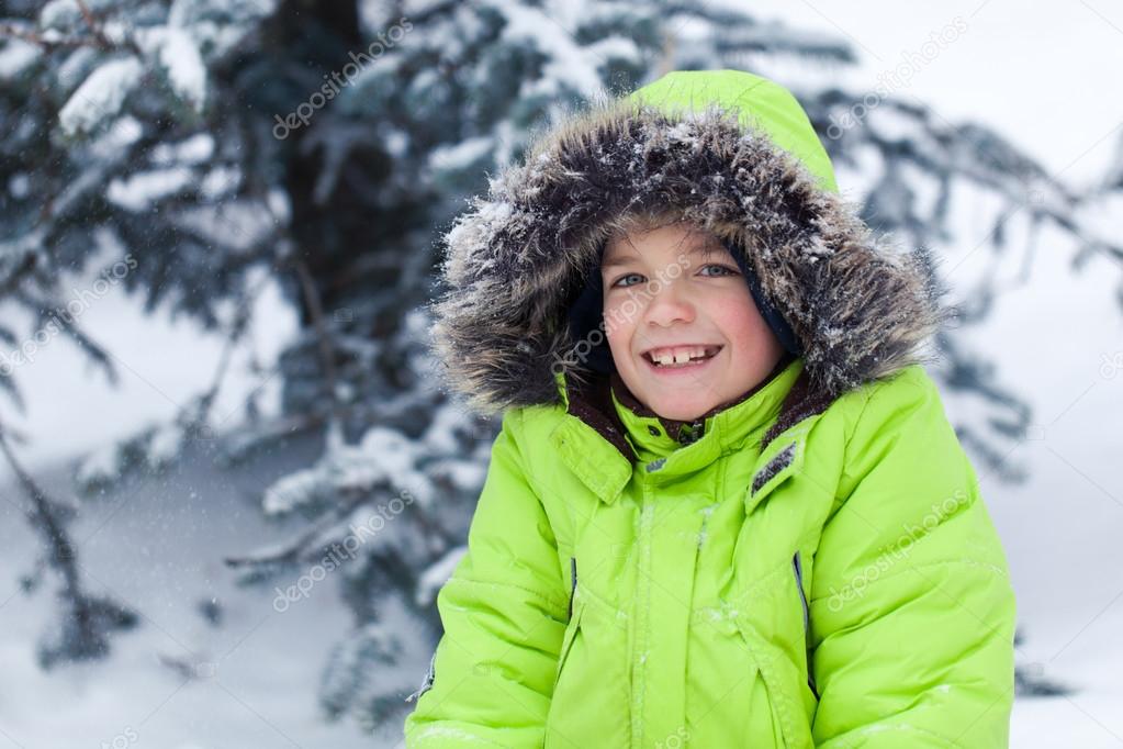 Portrait of pretty happy boy in winter snow park