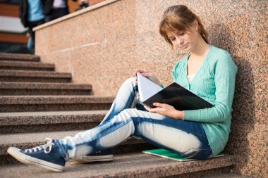 Merdivenlerde oturan ve Not okuma kız