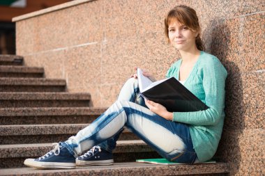 Merdivenlerde oturan ve Not okuma kız
