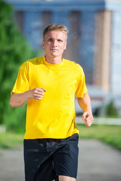 Sportlicher Mann joggt im Stadtpark. Fitness im Freien. — Stockfoto