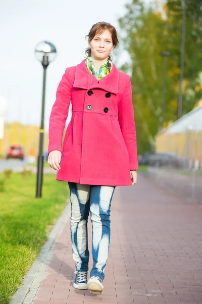 Красива жінка в червоному пальто, що йде осінньою вулицею . — стокове фото