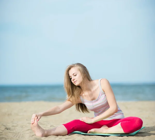 Mladá dáma praktikující jógu. Cvičení u pobřeží moře oceánu. — Stock fotografie
