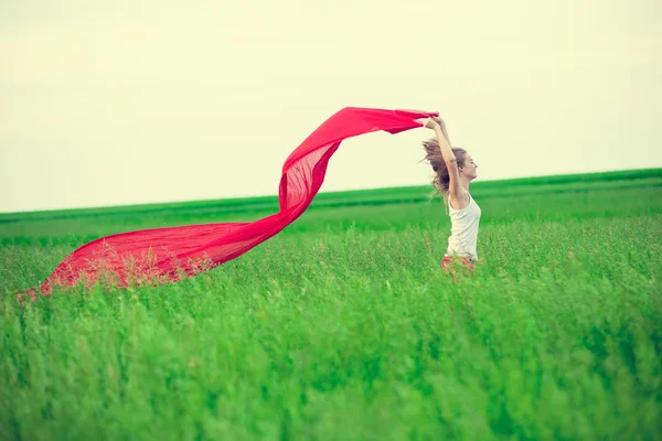 Jeune femme courant avec des tissus dans un champ vert. Femme avec écharpe . — Photo