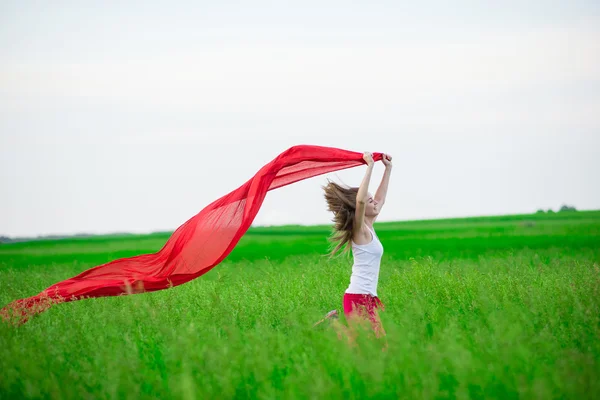 Young lady runing with tissue in green field. Woman with scarf. — Stock Photo, Image