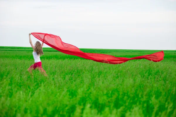 Jeune femme courant avec des tissus dans un champ vert. Femme avec écharpe . — Photo