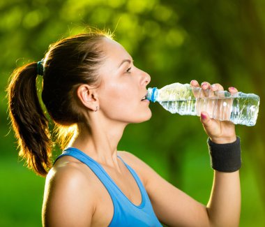 Spor sonrası su içen genç bir kadın.