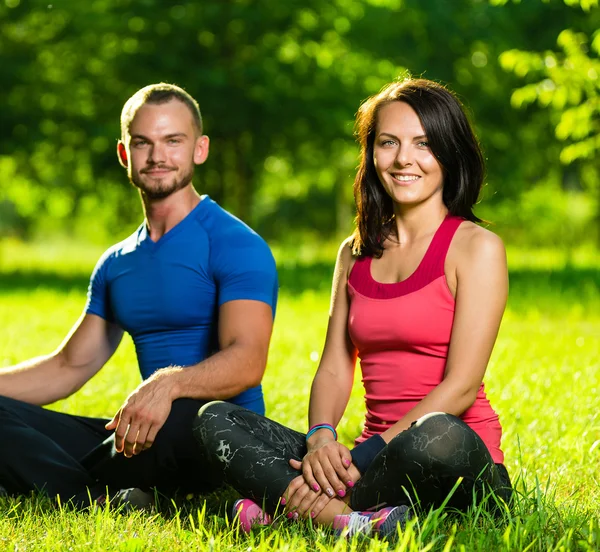 Hombre y mujer jóvenes haciendo yoga en el soleado parque de verano —  Fotos de Stock