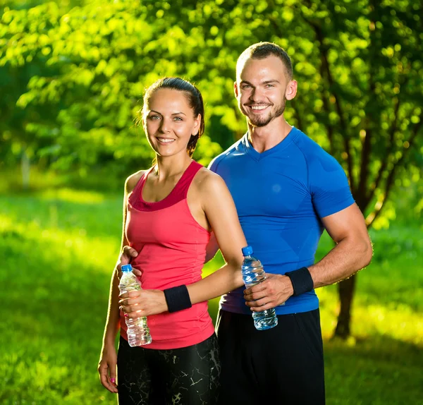 Homme et femme buvant de l'eau de bouteille après l'exercice sportif de remise en forme — Photo