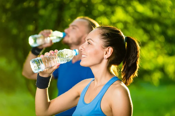 Man and woman drinking water from bottle after fitness sport exercise — Stock Photo, Image