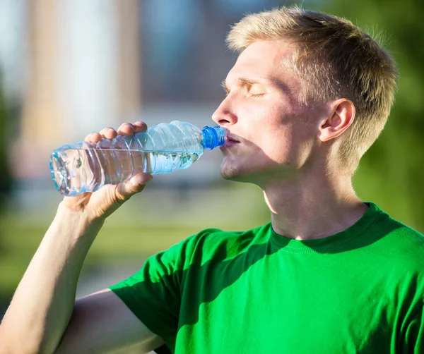 Moe man drinkwater uit een plastic fles na fitness — Stockfoto
