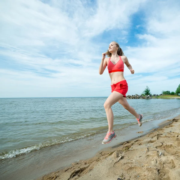 Jovencita corriendo en la soleada playa de arena de verano. Entrenamiento. Corre. —  Fotos de Stock