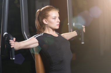 Bir makine üzerinde silah egzersizleri yapıyor spor salonunda kadın