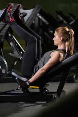 Bacaklar için ağırlıklar basın makine kullanan sportif kadın. Spor salonu.