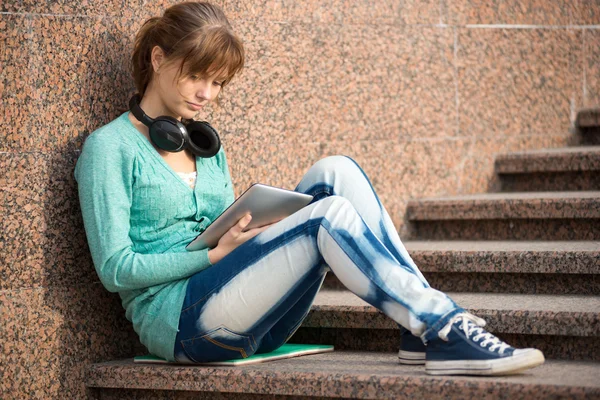 Linda jovem estudante com bloco de notas e fones de ouvido. Estudante exterior . — Fotografia de Stock