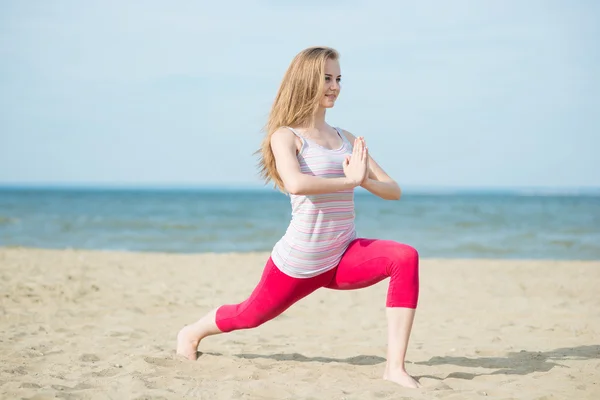 Mladá dáma praktikující jógu. Cvičení u pobřeží moře oceánu. — Stock fotografie