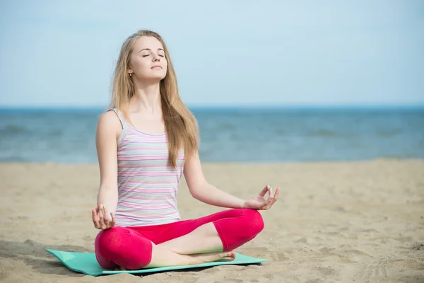 Jovencita practicando yoga. Entrenamiento cerca de la costa del mar . — Foto de Stock