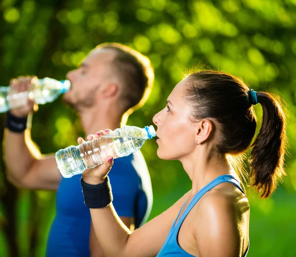 Homme et femme buvant de l'eau de bouteille après l'exercice sportif de remise en forme — Photo