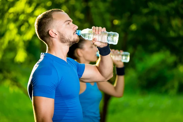 Mężczyzna i kobieta wody pitnej z butelki po treningu sportowego fitness — Zdjęcie stockowe