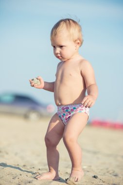 Şirin Bebek denize yakın kum plajındaki oyuncaklar ile oynama.