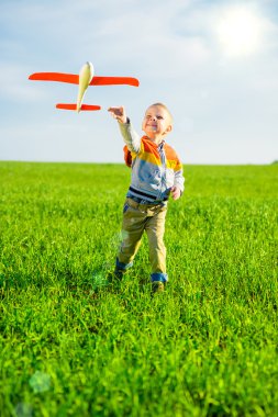 Oyuncak uçak mavi yaz gökyüzü ve yeşil alan arka plan karşı oynamaktan mutlu çocuk.
