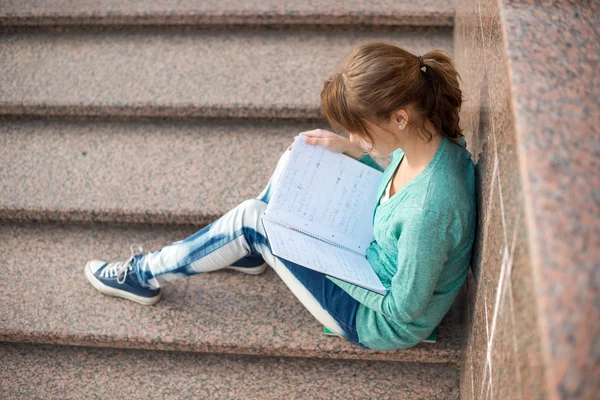 Girl sitting on stairs and reading note — Stock Photo, Image