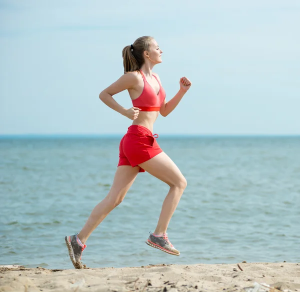 Молода леді біжить на сонячному літньому піщаному пляжі. Тренування. Джог — стокове фото
