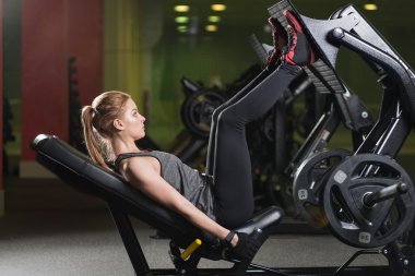 Bacaklar için ağırlıklar basın makine kullanan sportif kadın. Spor salonu.