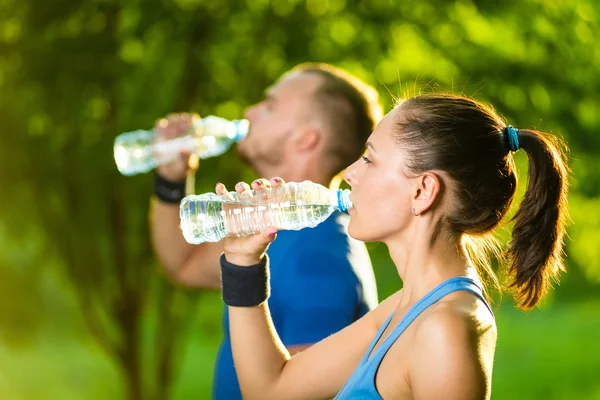 Hombre y mujer bebiendo agua de la botella después del ejercicio deportivo de fitness —  Fotos de Stock