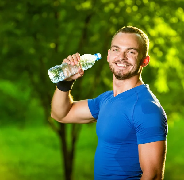 Athletic mogen man dricksvatten från en flaska — Stockfoto